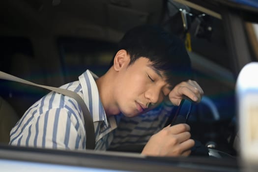 Tired man falls asleep on steering wheel. Unsafe driving from fatigue and drowsiness of the driver