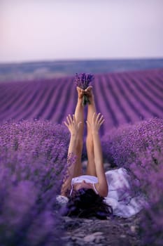 Lavender field woman's legs emerging from the bushes, holding a bouquet of fragrant lavender. Purple lavender bushes in bloom, aromatherapy