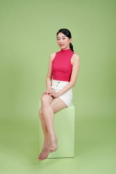 A seated young smiling business woman against green background