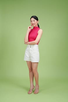 Full length image of young Asian woman posing on green background