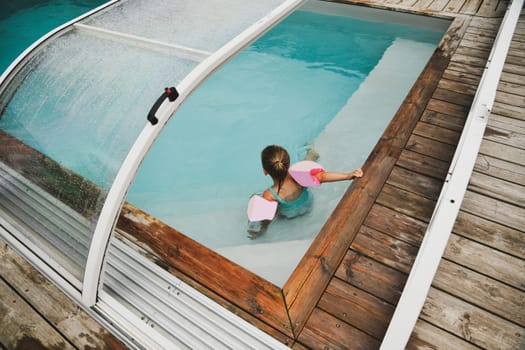 Girl in inflatable armbands iplaying n the pool