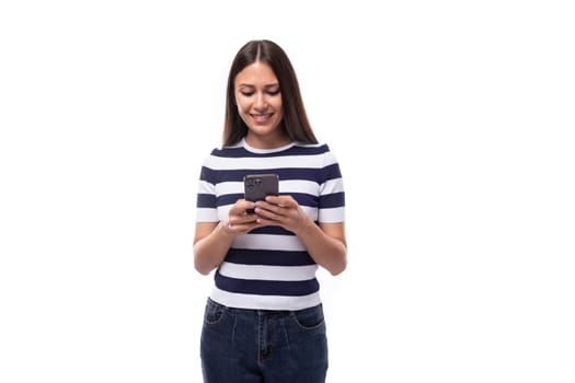 young brunette european lady of slim build dressed in a striped summer t-shirt chatting on a smartphone.