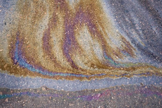 An oily iridescent stain of gasoline or oil spilled on the road