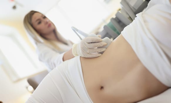 Doctor doing ultrasound examination of kidneys to woman patient in clinic closeup. Diagnosis of diseases of urinary system concept