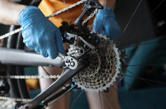 Technician in protective gloves repairing rear wheel of bicycle closeup. Bicycle repair and maintenance concept