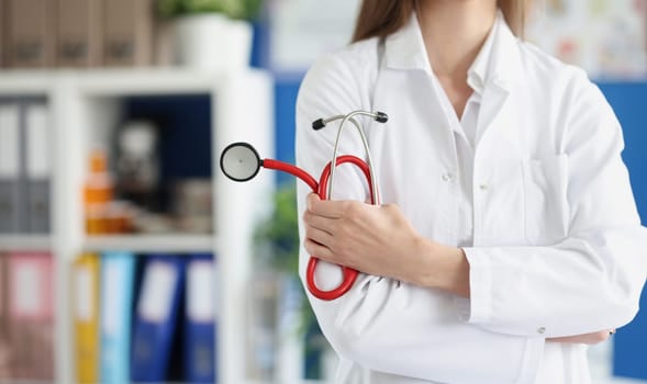 Woman doctor holding red stethoscope in clinic closeup. Quality medical care concept