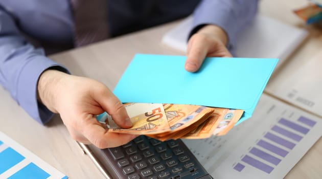 Saving Cash Wealth Business Budget Report Concept. Male Office Manager Review Financial Business Data. Businessman Put Euro Money in Blue Envelope. Analyzes Banking Profit with Chart, Calculator