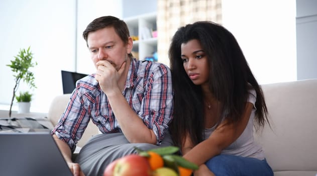 Portrait of lovely couple spending time together indoors. Middle-aged man surfing on modern computer. Latino american female sitting near. Leisure and technology concept