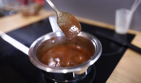 Close-up of aluminum pot with tasty brown custard for cake. Silicon spatula. Confectionery and homemade sweets. Cocoa pudding in bowl. Bakery and food concept