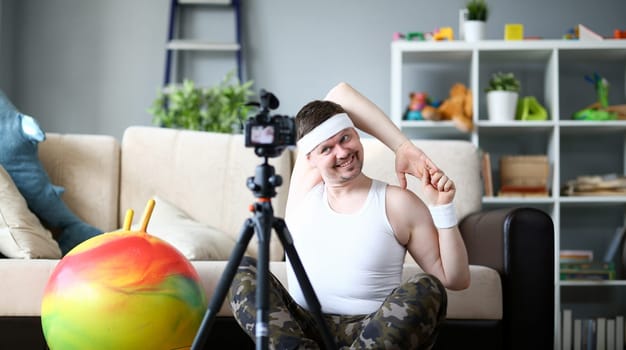 Happy Blogger Doing Exercise on Digital Camera. Smiling Man Practice Exercise for Sport Blog. Cheerful Male Recording Video at Apartment. Guy Training Hands and Shooting on Camcorder Indoor