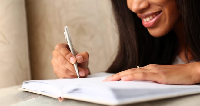 Arm of black woman write story in notebook preparing for college