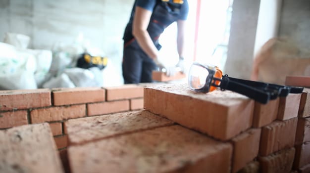 Focus on construction site made of red bricks and concrete. Professional engineer stacking special equipment and tools to properly fulfill construction. Building concept