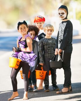 Children, halloween or trick and treat portrait outdoor in neighborhood for fun and dress up. A group of young kids together for happiness, celebrate holiday and diversity with candy or sweets.