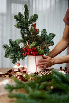 Woman making Christmas arrangement with fir branches. craft handmade decor.