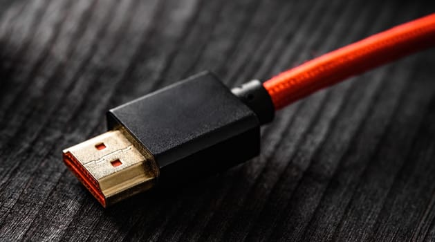 Red wire with HDMI connector, on a dark table, close up view