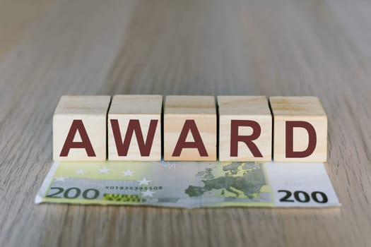 Award word on a wooden cubes blocks, money 200 Euro banknotes. Management big salary career concept.