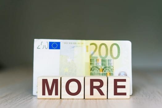 More word on a wooden cubes blocks, money 200 Euro banknotes. Management big salary career concept.