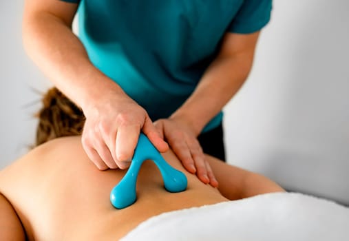 Skilled massage therapist rehabilitologist doing back massage with special massage accessories in a rehabilitation parlor