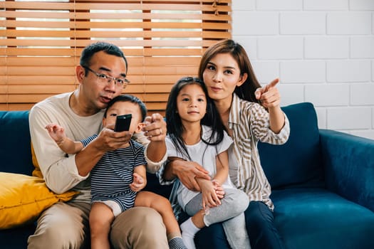 A young family enjoys quality time watching TV at home. The father mother brother and sister share moments of joy on the sofa epitomizing togetherness relaxation and family bonding.
