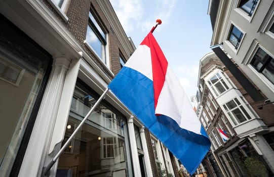 Waving Netherlands flag on fasad building against Blue Sky