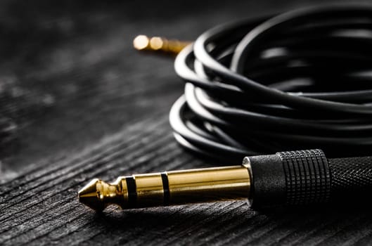 audio cable with Jack and mini jack connectors, on a dark table, close up view