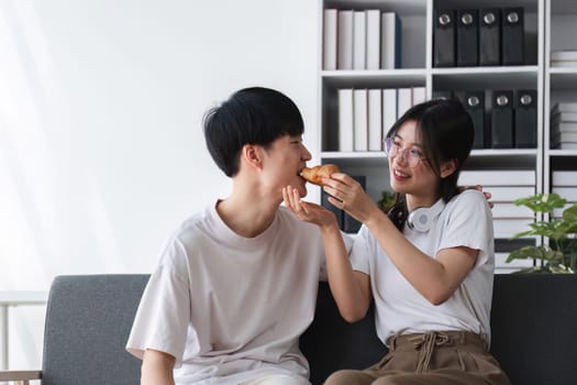 A smiling young couple of boys and girls were sitting on the sofa in the living room, teasing each other with fun..