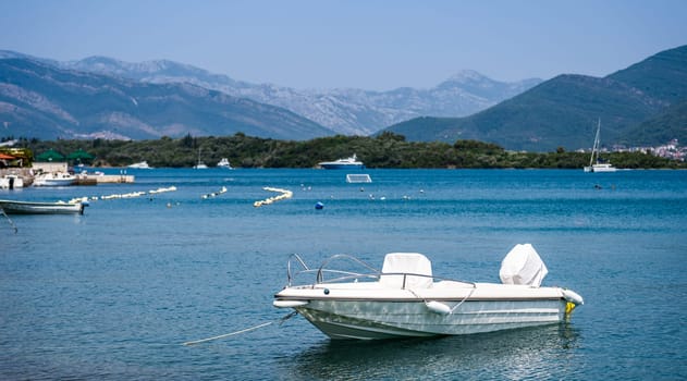 White boat in Adriatic sea, Montenegro with mountains and forest on background. Vessel transportation in beautiful Mediterranean nature in sunny day