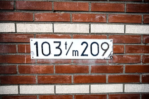 Address sign on residential building brick wall with numbers. House identification signboard on stone facade