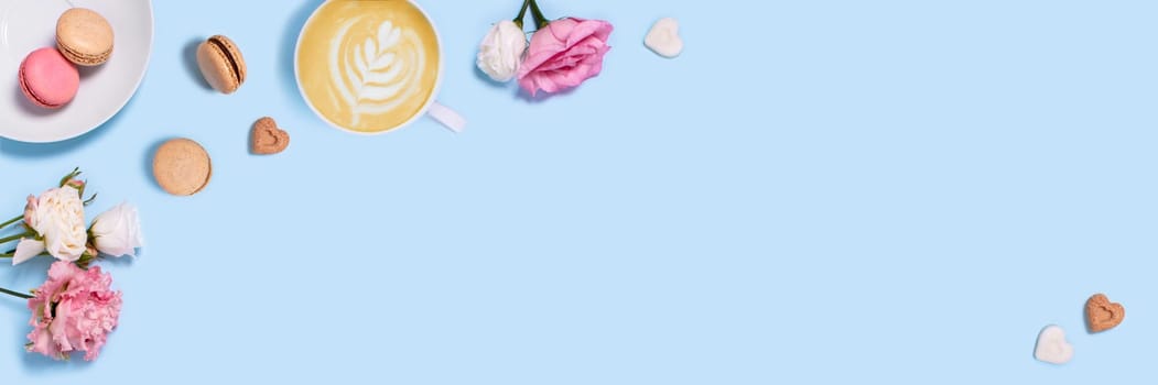 Blue background with macaroons and a Cup of coffee surrounded by peonies and roses. Top view with space for your text.