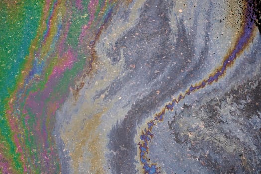 A marble texture of a rainbow spill of gasoline on a sidewalk in a puddle as a background.