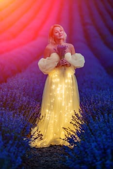 Woman in yellow glowing dress holds bouquet in lavander field. Illustrating woman with flowers. She is holding a bouquet of purple flowers in her hands. Aromatherapy concept, lavender oil, photo session in lavender
