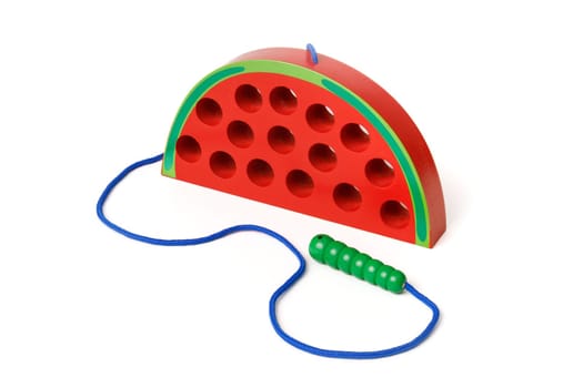 Kid's wooden toy in the shape of a red watermelon with a worm on a rope, toy for developing fine hand motor skills, isolated on white background.