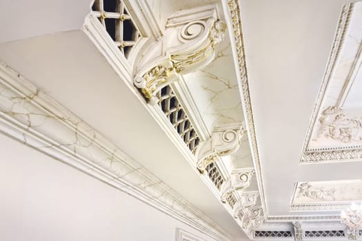 White plaster molding elements with gold veins for decorating the ceiling in a classic style.