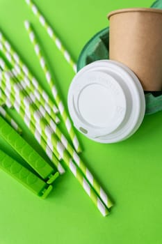 This image features a disposable coffee cup with a white lid, green striped straws, and a bright green background