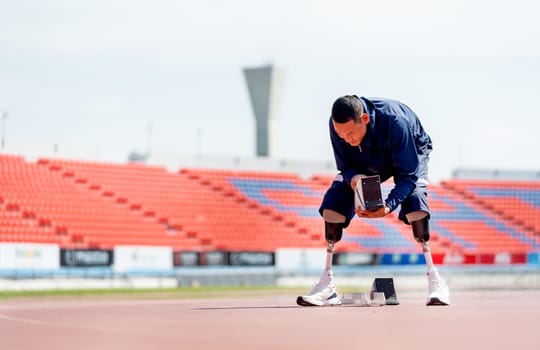 Wide shot of sport man athlete with a prosthesis on his leg prepare of the running equipment on the track at the stadium. Sport concept.