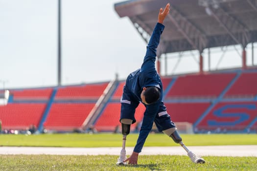 Sport man athlete with a prosthesis on his leg action of warm-up the body with stand and  do tab switch on foot in area of grass field at the stadium, sport concept.