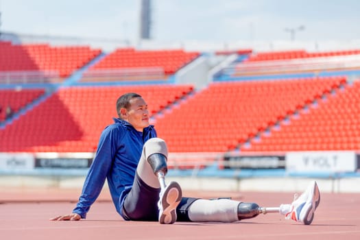 Sport man athlete with a prosthesis on his leg sit on the track and look forward to relax after exercise at the stadium. Sport concept.