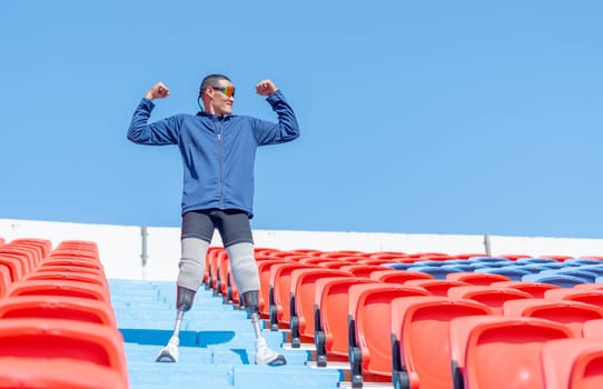 Sport man athlete prosthesis legs stand on stairs with action of push his muscles on amphitheater in the stadium with day light.