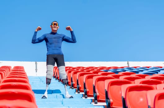 Side view of sport man athlete prosthesis legs stand on stairs with action of happy and celebration on amphitheater in the stadium with day light.