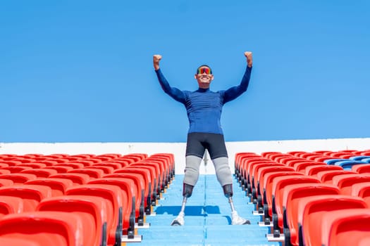 Sport man athlete prosthesis legs stand on stairs with action of happy and celebration on amphitheater in the stadium with day light.