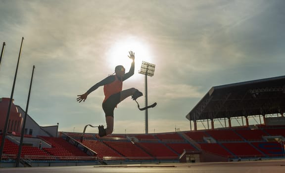 Sport man athlete prosthesis legs jump up in front of sun light in the afternoon of the stadium.