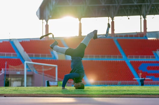 Sport man athlete prosthesis legs push head on grass field and separate legs in the stadium with soft light in evening.