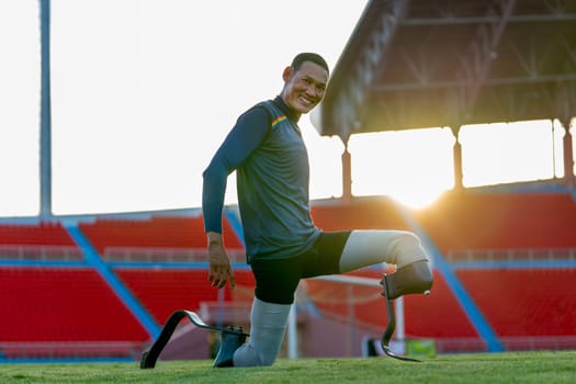 Close up side view sport man athlete prosthesis legs stay in the position of stretching also look at camera in the stadium with soft light of evening.
