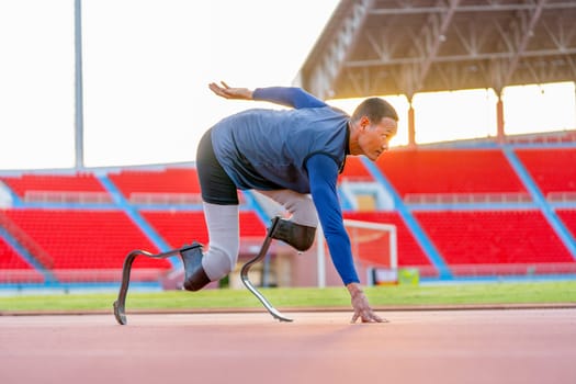Sport man athlete prosthesis legs stay in the position of start running on the track and look forward at the stadium with soft light of evening.