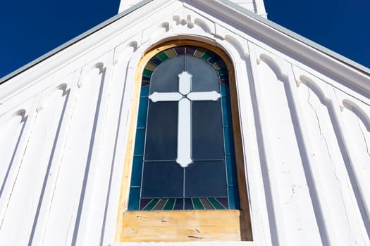Wooden White Church Stained glass window with Cross, Blue Sky On Background. Christian Religious Holiday Easter or Radonitsa. Horizontal Plane. High quality photo