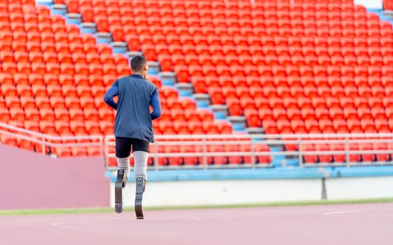 Wide shot back of sport man athlete prosthesis legs run or jogging in the track of the stadium with day light.