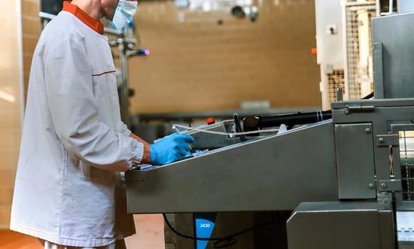 Two workers start making blocks of cheese in a factory. Worker on a cheese production line.