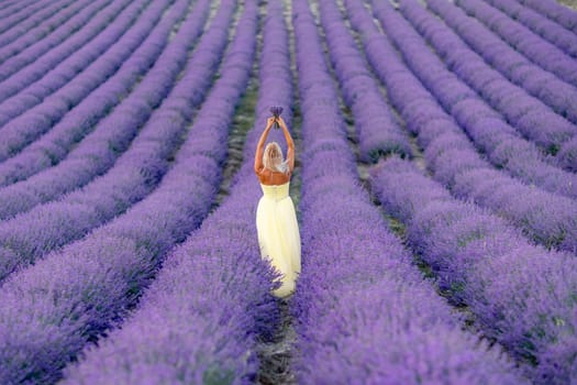 Woman lavender field. Lavender field happy woman in yellow dress in lavender field summer time at sunset. Aromatherapy concept, lavender oil, photo session in lavender.