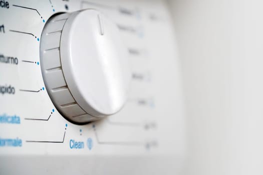 Washing machine with different modes of washing, spinning and rinsing clothes in the house, an assistant for hygiene and cleanliness, white control buttons close-up.