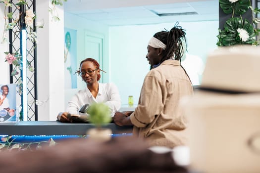 Shopping mall employee scanning clothes at cash register while customer paying for purchase. Store assistant using pos terminal scanner at counter desk while client buying shirts